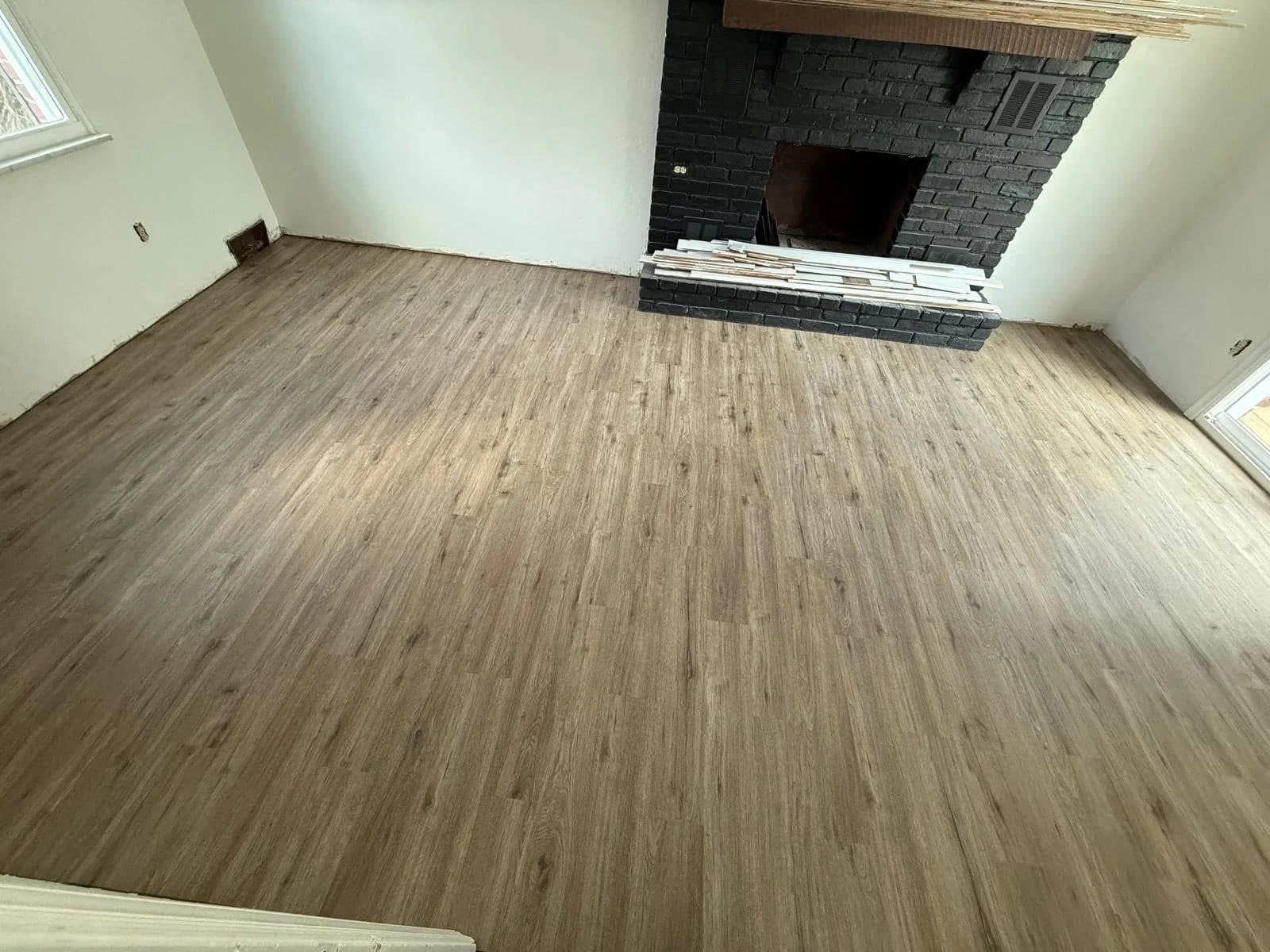Wood-look flooring fitted around a black brick fireplace
