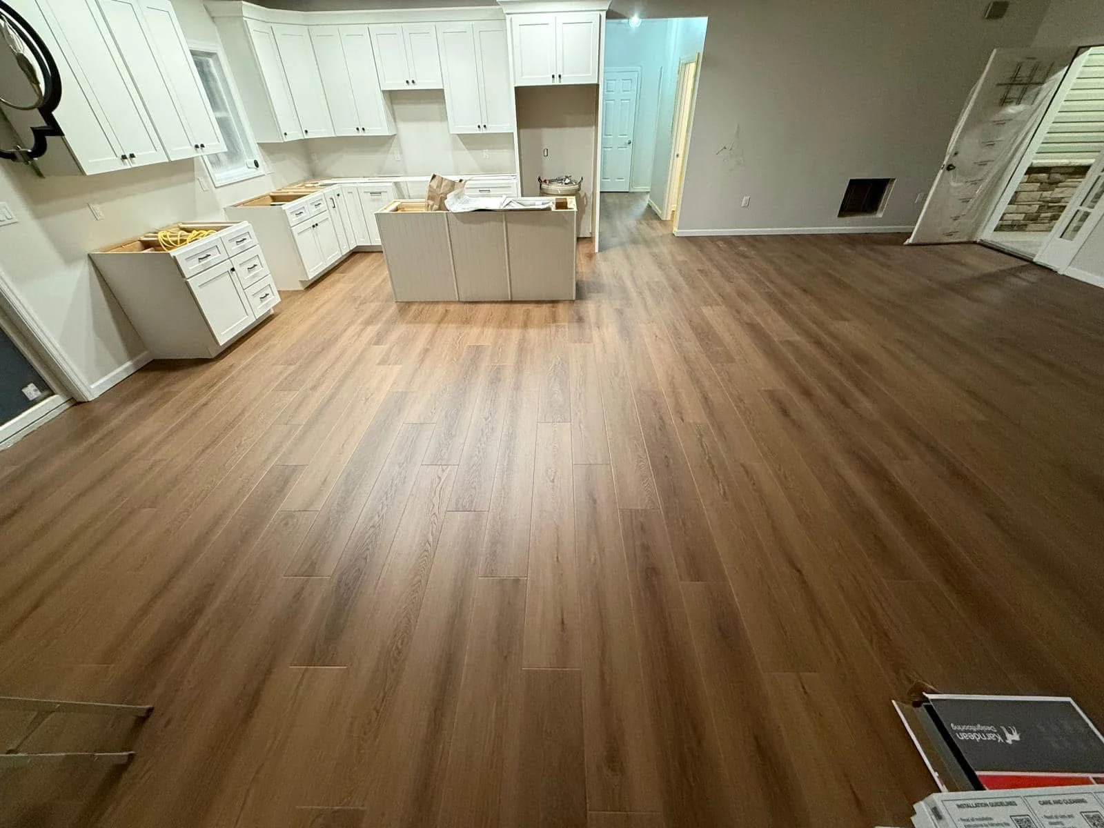 Wood-look plank flooring across a kitchen with white cabinets