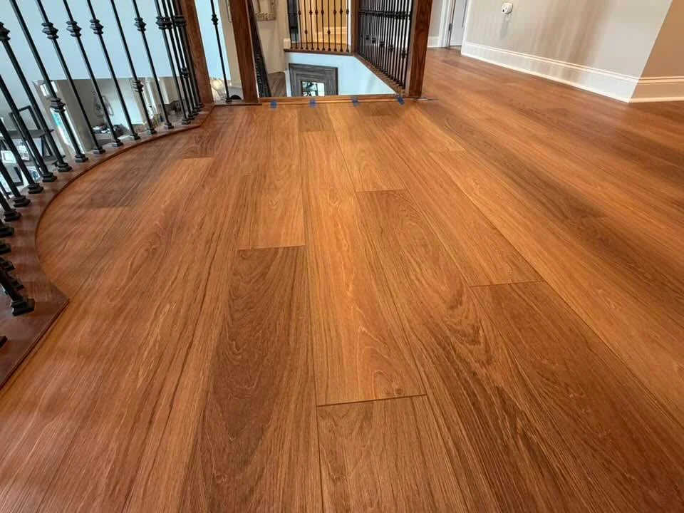 Warm wood-look plank flooring on an upstairs landing beside iron railings